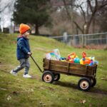 A Young Boy Is Pulling His Wagon Up A Hill